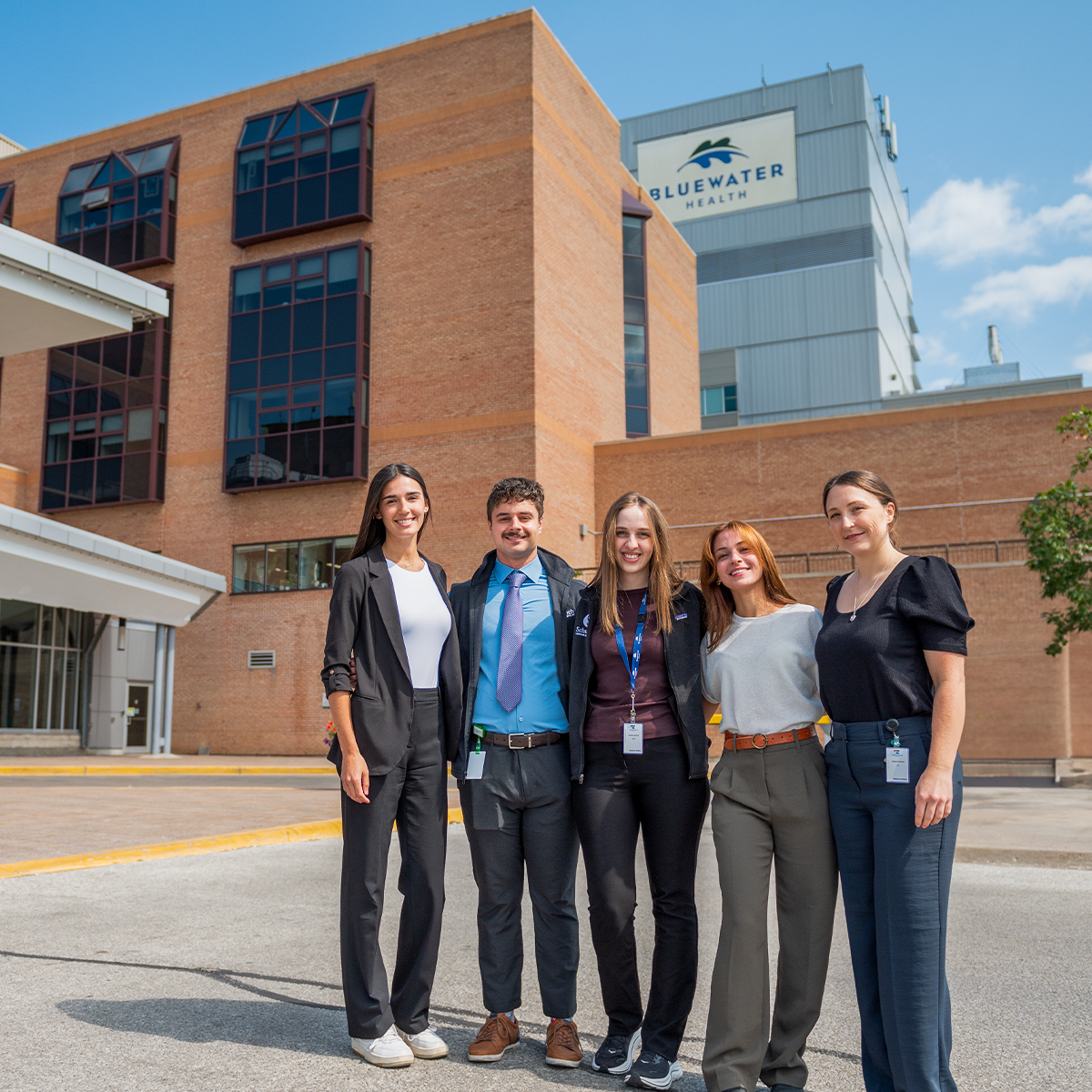 A group shot of five clinicians outside the glass building