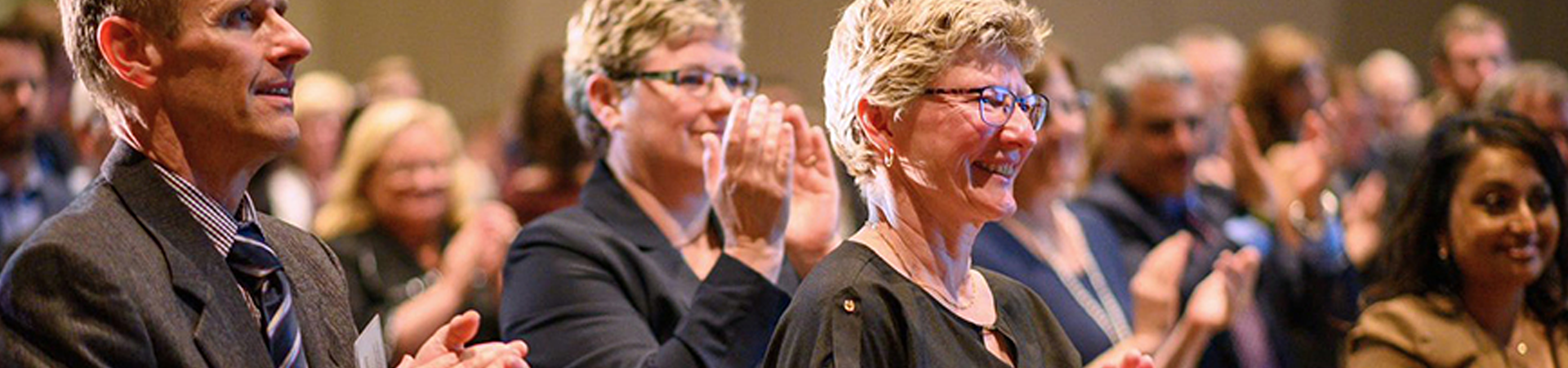 An audience applauding and smiling at a formal event