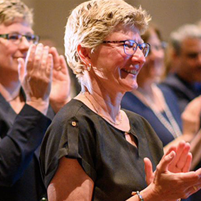 An audience applauding and smiling at a formal event