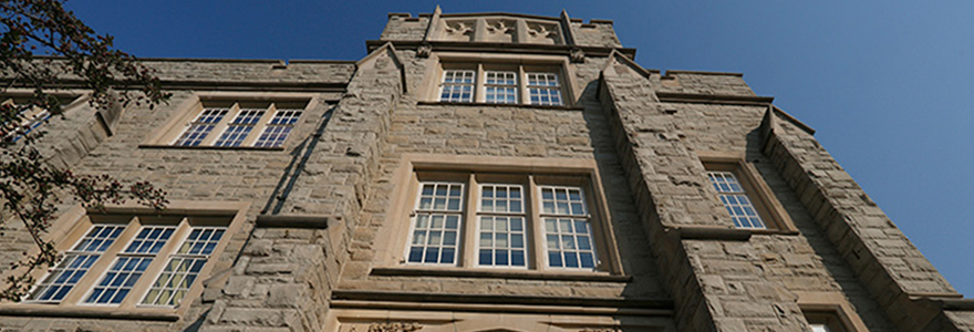 An artistic shot of a Schulich old stone building, looking up at the sky