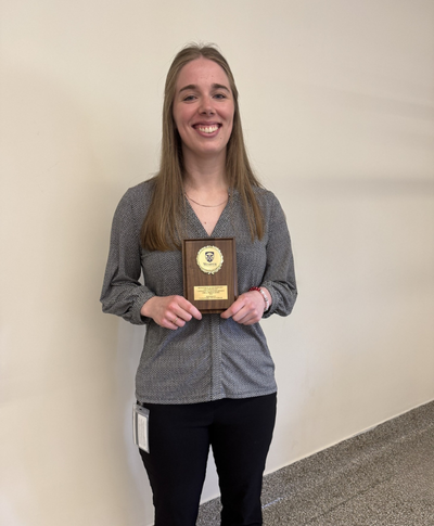 Cassandra Edgar, Award Recipient, holding plaque and smiling at camera