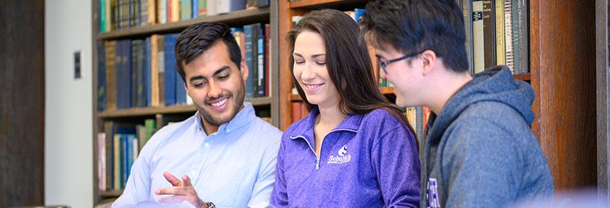 Photograph of three students looking at a book