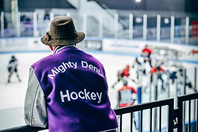Photograph of Dr. Kenneth Wright at the hockey arena wearing his Mighty Dents hockey jacket