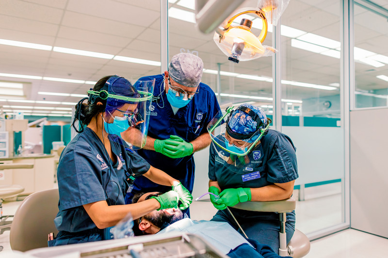 Schulich Dentistry students and a faculty member treating a patient in a dental clinic