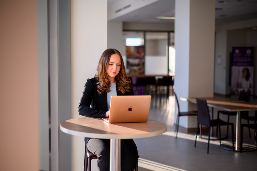 A student working on a laptop at a table on Western's campus