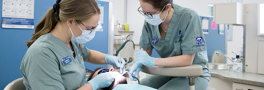 Photograph of two students working on a patient in the dental suite