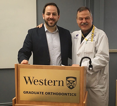 Photograph of Dr. Papadopoulos at a podium with Dr. Mamandras